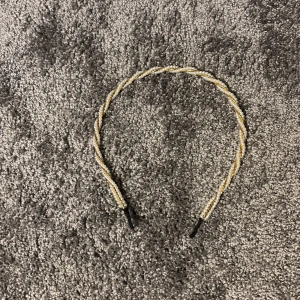 Glittrigt tvinnat diadem i guld - Snyggt diadem med tvinnad design i guld och silverglittrande material. Perfekt accessoar för att lyfta din look med lite extra bling. Smal och lätt modell med svarta ändar för bekväm passform.