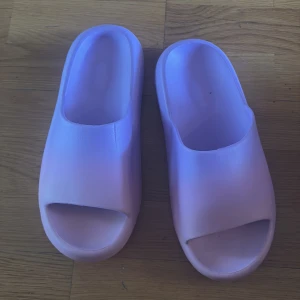 Ljuslila sandaler med öppen tå - Chunky ljuslila sandaler i syntetmaterial med öppen tå och platt sula. Perfekta för sommardagar eller att chilla hemma. Snygg minimalistisk design och riktigt bekväma att glida runt i.