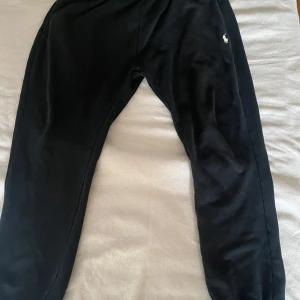 Svarta mjukisbyxor Polo Ralph Lauren - Svarta mjukisbyxor från Polo Ralph Lauren med klassisk broderad logga på benet. Byxorna har resår i midjan och vid bensluten, samt en bakficka. Perfekta för chill eller träning, tillverkade i mjuk bomull för extra komfort.
