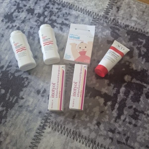 Hudvårdsprodukter för barn och skyddande kräm - Paket med två ACO special puder, två Inotyol zinksalvor och en tub ACO skyddande kräm. Produkterna är i vita och röda förpackningar. Inotyol-salvan är känd för sin vårdande effekt och ACO-produkterna är milda mot huden. Frida Baby Windi ingår också.  Där paketet är öppet och en förbrukats.