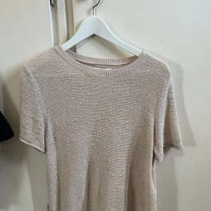 Beige stickad kortärmad tröja - Snygg beige stickad tröja med korta ärmar och rund hals. Perfekt för dig som gillar en enkel och clean stil. Tröjan har en avslappnad passform och är superenkel att matcha med jeans eller kjol.