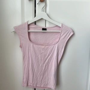 Ljusrosa topp från Gina Tricot XS - Supersöt ljusrosa topp från Gina Tricot i storlek XS. Toppen har en fyrkantig urringning och är ärmlös med breda axelband🩷