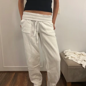 Vita mjukisbyxor med snörning - Superbekväma vita mjukisbyxor med bred resår i midjan och snörning framtill. Byxorna har raka ben, stora fickor fram och bak samt är gjorda i mjukt bomullstyg. Perfekta för chill dagar eller när du vill vara extra comfy.