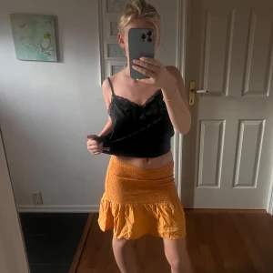 Gul volangkjol med smock - Superfin gul kortkjol med smock i midjan och volang nertill. Kjolen har en lätt och luftig känsla, perfekt för varma dagar. Snygg att matcha med crop tops eller stickade tröjor. Passar dig som gillar färg och vill sticka ut lite extra.