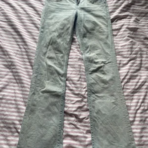 Ljusblå bootcut jeans från H&M Divided - Säljer ett par ljusblå bootcut jeans från H&M Divided i storlek 34. Jeansen har klassisk femficksdesign, bakfickor med lock och knapp. En av bakfickorna har även en liten tuggummifläck. Använda ganska många gånger.