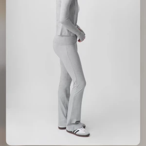 Grå bootcut mjukisbyxor Gina Tricot - Snygga ljusgrå mjukisbyxor från Gina Tricot i bootcut-modell. Byxorna har hög midja med bred linning och är gjorda i mjukt bomullsmaterial med lite stretch. Perfekta för en chill och avslappnad look.