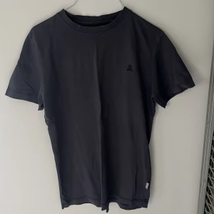 Svart t-shirt från Scalpers XS - Svart t-shirt från Scalpers i mjuk bomull. Klassisk passform med rund hals och korta ärmarnas. Diskret broderad dödskalle på bröstet ger en cool detalj. Perfekt basic att ha i garderoben. Storlek XS