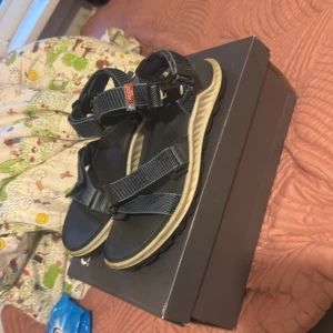 Mörkblå sandaler från Ecco - Snygga mörkblå sandaler från Ecco med justerbara remmar och robust svart sula. Perfekta för sommaren med bekväm passform och sportig look. Remmarna är i slitstark syntet och sulan har bra grepp för äventyr utomhus.