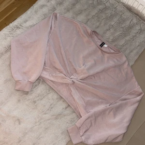 Ljusrosa croppad sweatshirt med knut - Superfin ljusrosa croppad sweatshirt från Divided. Tröjan har lång ärm, rund halsringning och en snygg knutdetalj framtill. Mjuk bomullskänsla och breda muddar vid ärmslut. Perfekt för en chill och trendig look.