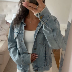 Ljusblå jeansjacka från j.lindeberg - Säljer en klassisk ljusblå jeansjacka från j.lindeberg. Jackan har raka linjer, bröstfickor med lock och knappar i metall. Perfekt oversized fit och snygg tvättad denim som passar till allt. Långärmad och med krage för en chill vibe.