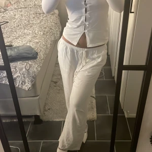 Vita linnebyxor med snörning - Säljer ett par fräscha vita linnebyxor med avslappnad passform och dragsko i midjan. Byxorna har raka, vida ben och elastisk midja för extra komfort. Perfekta för en chill och stilren look.