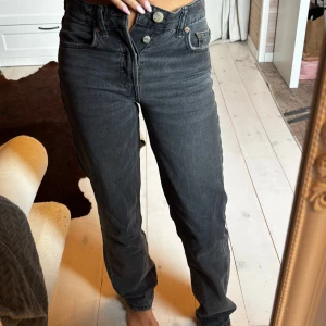 Svarta raka jeans från Zara - Säljer ett par svarta jeans från Zara med raka ben och medelhög midja. Jeansen har klassisk femficksdesign, knäppning med flera knappar och är tillverkade i bomull. Perfekta för en chill och stilren look.
