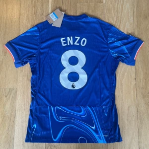 Chelsea 24/25 Hemma kit - Chelsea 24/25 Hemma kit med Enzo Fernandes på ryggen, oanvänd i storlek M men passar även S, Spelar-material med tags kvar