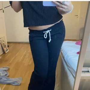 Svarta linnebyxor med snörning - Säljer ett par svarta linnebyxor med avslappnad passform och vit snörning i midjan. Byxorna har resår i midjan och raka ben, perfekta för en chill och stilren look. Materialet är svalt och skönt, passar grymt till sommaren.