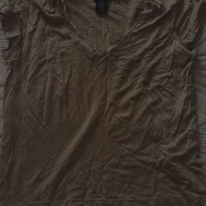 Beige v-ringad kortärmad topp - En enkel och stilren beige topp med v-ringning och korta ärmar. Perfekt att matcha med jeans eller kjol för en avslappnad look. Tillverkad i mjukt bomullsmaterial som känns skönt mot huden.