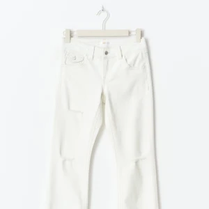 Vita flare jeans med slitningar - Säljer ett par vita jeans med flare ben och snygga slitningar vid knäna. Jeansen har klassisk femficksdesign och normal passform. Perfekta för dig som vill ha en fräsch och trendig look.