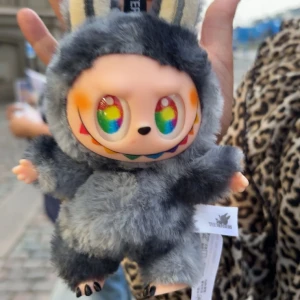 Pop Mart The Monsters fluffig lafufu - Supergullig lafufu  från Pop Mart The Monsters, formad som en liten figur med fluffig päls i grått och svarta detaljer. Väskan har öron, regnbågsfärgade ögon och ett brett leende. Perfekt accessoar för dig som vill sticka ut den är väldigt svårt att få tag på jag fick beställa 6 lafufu packet för att få den så det är därför den säljs för så högt pris men pris kan diskuteras 💞💞
