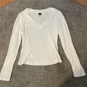 Topp  - En basic vit långärmad topp från Shein i storlek XS. Toppen har en snygg v-ringning och är figurnära i modellen. Perfekt att styla med jeans eller kjol för en clean look. Materialet är mjukt och stretchigt, vilket gör den bekväm att bära hela dagen.