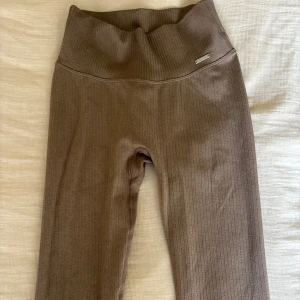 Ribbade beigea leggings från Aim'n XS - Säljer ett par ribbade leggings från Aim'n i en snygg beige nyans. De är högmidjade och har en tight passform som sitter skönt. Perfekta för träning eller chill, med diskret Aim'n-logga framtill. Materialet är stretchigt och mjukt mot huden.