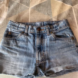 Blå jeansshorts - Snygga blå jeansshorts med klassisk femficksdesign och rå, fransig kant nedtill. Shortsen har bälteshällor och dragkedja med knapp framtill. Perfekta för varma dagar och ger en avslappnad vibe. 💙