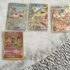 Pokémonkort: Charizard, Eevee, Jolteon m.fl. - Samling med fyra Pokémonkort, inklusive den klassiska Charizard och japanska kort med Eevee och Jolteon. Perfekt för samlare och fans av Pokémon! Korten är i skyddsplast och har färgstarka illustrationer som gör dem extra coola.