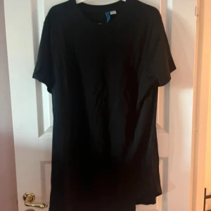 Svart basic t-shirt - En enkel svart t-shirt med rund hals och korta ärmar. Perfekt för en clean och stilren look. T-shirten är rak i modellen och passar till det mesta. Materialet känns mjukt och bekvämt mot huden.