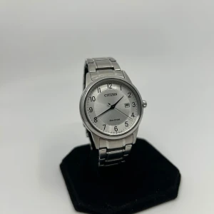 Citizen Eco-Drive silverklocka - Stilren klocka från Citizen med silverfärgad urtavla och armband i metall. Klassisk rund form, tydliga svarta siffror och datumvisning. Eco-Drive-teknik som laddas av ljus. Perfekt för dig som gillar enkel och tidlös design.