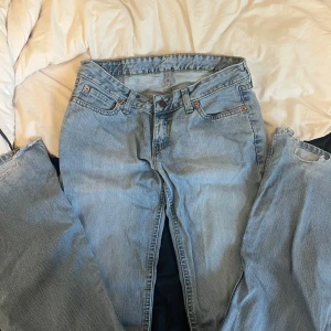 Levi's 505 ljusblå jeans - Klassiska Levi's 505 jeans i ljusblå denim, raka med lite utvängning. Jeansen har fem fickor, gylf med dragkedja och den ikoniska läderpatchen bak i midjan. Perfekta för en avslappnad och tidlös stil.