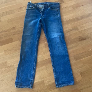 Levi's 501 Premium jeans blå 32/34 - Klassiska Levi's 501 Premium jeans i blå tvätt med raka ben och normal passform. Jeansen har fem fickor, knappgylf och snygga slitningar för en cool vintagekänsla. Tillverkade i robust bomullsdenim, perfekt för dig som gillar tidlös stil.