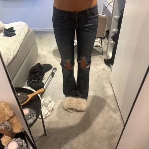 Blå Levis bootcut jeans med slitna knän - Säljer ett par blå Levis vintage bootcut jeans med  slitningar över båda knäna. Jeansen har låg midja. Materialet är denim och passformen är normal med lätt utsvängda ben. 