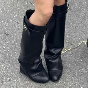 Svarta höga boots med kilklack - Säljer mina snygga folded shaft kilklack stövlar som liknar de shark boots från Givenchy 🤩 Använda på 2 konserter (de två första bilderna) Har en genomskinlig gummisula för trampytan. Gick bra att ha på sig länge för mig som aldrig gått i klackar tidigare. Slitet där bak men inget man ser när de är på. Pris kan diskuteras 💞 Hör av er vid frågor!
