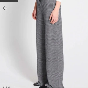 Randiga vida byxor med snörning - Supersköna vida byxor med svartvita tunna ränder och dragsko i midjan. Byxorna har loose fit och är tillverkade i ett mjukt, stretchigt material som känns riktigt bekvämt. Perfekta för en chill och avslappnad stil.