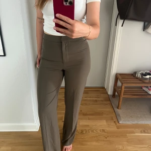 Bruna vida byxor från H&M, strl 36 - Snygga bruna byxor från H&M i storlek 36. De är högmidjade med vida ben och har en stilren look med dold dragkedja framtill. Perfekta för dig som gillar en clean och trendig stil. 