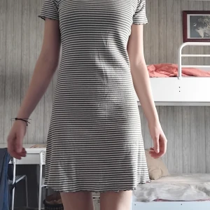 Randig ribbad klänning i bomull - Superfin ribbad klänning med smala gröna och vita ränder. Modellen är kortärmad och har en rak, något figurnära passform. Mjuk och stretchig bomullskvalitet som är skön att ha på sig. Perfekt för dig som gillar en enkel men snygg stil.