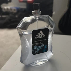 Adidas Ice Dive Eau de Toilette 80ml - Fräsch parfym från Adidas, Ice Dive, i en transparent och sportig flaska med svarta och blå detaljer. Flaskan har en unik, kantig form och sprayfunktion. Perfekt för dig som gillar en energisk och uppfriskande doft.