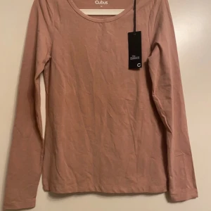 Långärmad - En riktigt fin långärmad topp från Cubus i storlek M i en vacker färg som kan beskrivas som gammalrosa. Helt ny och oanvänd – prislappen sitter kvar men utan angivet pris. Perfekt både till vardag och lite finare tillfällen! 