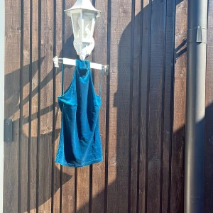 Blå halterneck linnetopp i sammet - Säljer en blå sammed  linnetopp med halterneck och tunna axelband. Toppen har en snygg sammetslook som fångar ljuset och ger en cool vibe. Perfekt för dig som vill sticka ut med en färgstark och trendig topp.