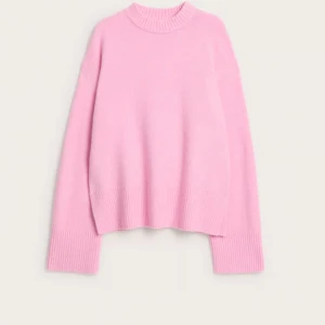 Ljusrosa stickad tröja med ribbade detaljer - Supermysig ljusrosa stickad tröja från Mango med ribbad hals, muddar och nederkant. Tröjan har en loose passform och långa ärmar, perfekt för att ge en chill vibe till din outfit. Materialet är mjukt och känns skönt mot huden.