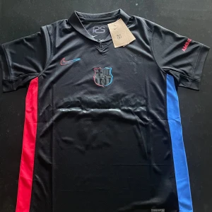 FC Barcelona Pedri #8 svart matchtröja Nike - Snygg FC Barcelona matchtröja med Pedri #8 på ryggen. Svart med röda och blå detaljer längs sidorna, klubbmärke och Nike-logga på bröstet. Kortärmad, tillverkad i Dri-FIT material som andas. Perfekt för dig som älskar Barca och vill ha en unik look.