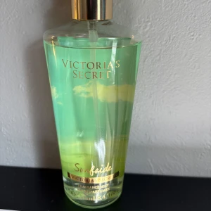 Victoria's Secret Surfside mist - Fräsch body mist från Victoria's Secret i doften Surfside. Flaskan är transparent med grönt och gult innehåll, guldigt lock och text. Doftnoter av passionsfrukt och drivved, berikad med aloe vera för en uppfriskande känsla. Perfekt för dig som gillar tropiska vibes. OBS! Gamla förpackningen. Har några år på nacken men liktar fortfarande gott. Knappt använd. 250 ml.