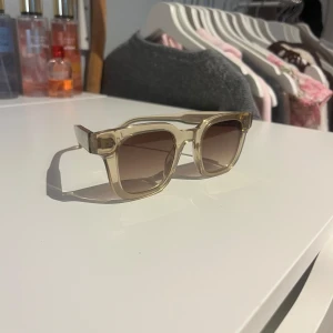 CHIMI solglasögon i 04 ecru  - Snygga solglasögon från CHIMI med transparent beige båge i 04 ecru. Glasen är bruna med tonad effekt och bågarna har en glittrig detalj på sidorna. Perfekt accessoar, super fina! 💗