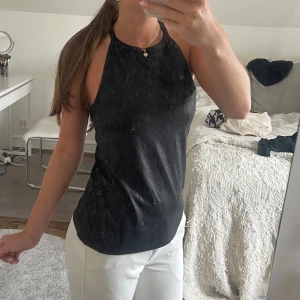 Svart ärmlös linnetopp med dragkedja - Snygg svart linnetopp med halterneck och rak passform. Toppen har en cool dragkedja i ryggen och är helt ärmlös. Materialet har en lätt glansig finish. Det är min spegel som är smutsig och inte toppen! 