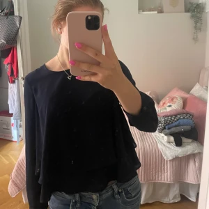 Mörkblå blus med volang från Zara - Säljer en stilren mörkblå blus från Zara Basic med rund halsringning och långa ärmar. Blusen har dubbla lager med volangdetalj. Perfekt att matcha med jeans eller kjol 🥰