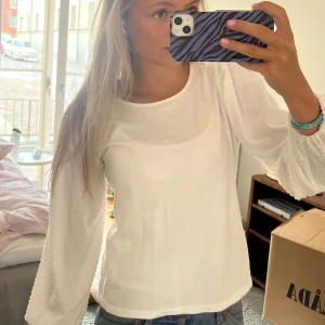 Vit blus - Supersöt vit blus med rund hals och långärmade, transparenta ärmar med diskret prickigt mönster. .