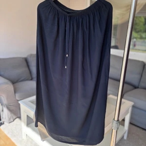 Svart kjol med snörning  - Svart kjol med dekorativ snörning framtill med silverfärgade detaljer. Kjolen har en rak och luftig passform.