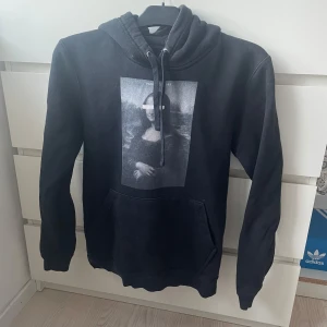 Svart hoodie med Mona Lisa-print - Svart hoodie från The Cool Elephant med stor Mona Lisa-print på bröstet. Inte använd super mycket men inte nyskick💘💘