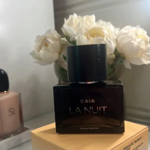 CAIA La Nuit Eau de Parfum - Säljer en CAIA La Nuit Eau de Parfum. Flaskan är mörk och fyrkantig med en stor svart rund kork och stilren silvertext. Parfymen har en lyxig och mystisk vibe, perfekt för dig som gillar eleganta dofter. Flaskan är tillverkad i glas. Knappt använd 