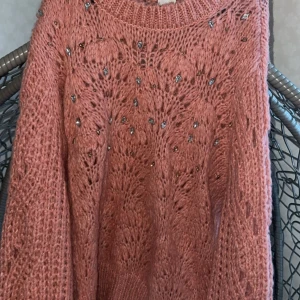 Rosa stickad tröja med paljetter - Säljer en fluffig rosa stickad tröja med glittriga paljettdetaljer. Tröjan har ett snyggt mönster i stickningen och är långärmad med rund hals. Perfekt för dig som gillar att sticka ut med lite extra bling och mysig känsla.