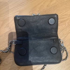 Svart Zadig&Voltaire väska  - Skit snygg Zadig väska i bra skick! Väskan har en lång kedjerem i silver och även en kortare kedja med Zadig-vingarna framtill. Perfekt storlek för mobilen och det viktigaste.
