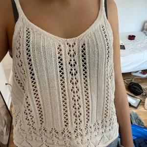 Vit stickad linnetopp med spetsdetaljer - Superfin vit stickad linnetopp med tunna axelband och snygga spetsdetaljer. Toppen har ett luftigt mönster med hålstickning och en v-ringad hals. Perfekt till jeans eller shorts för en chill sommarlook.